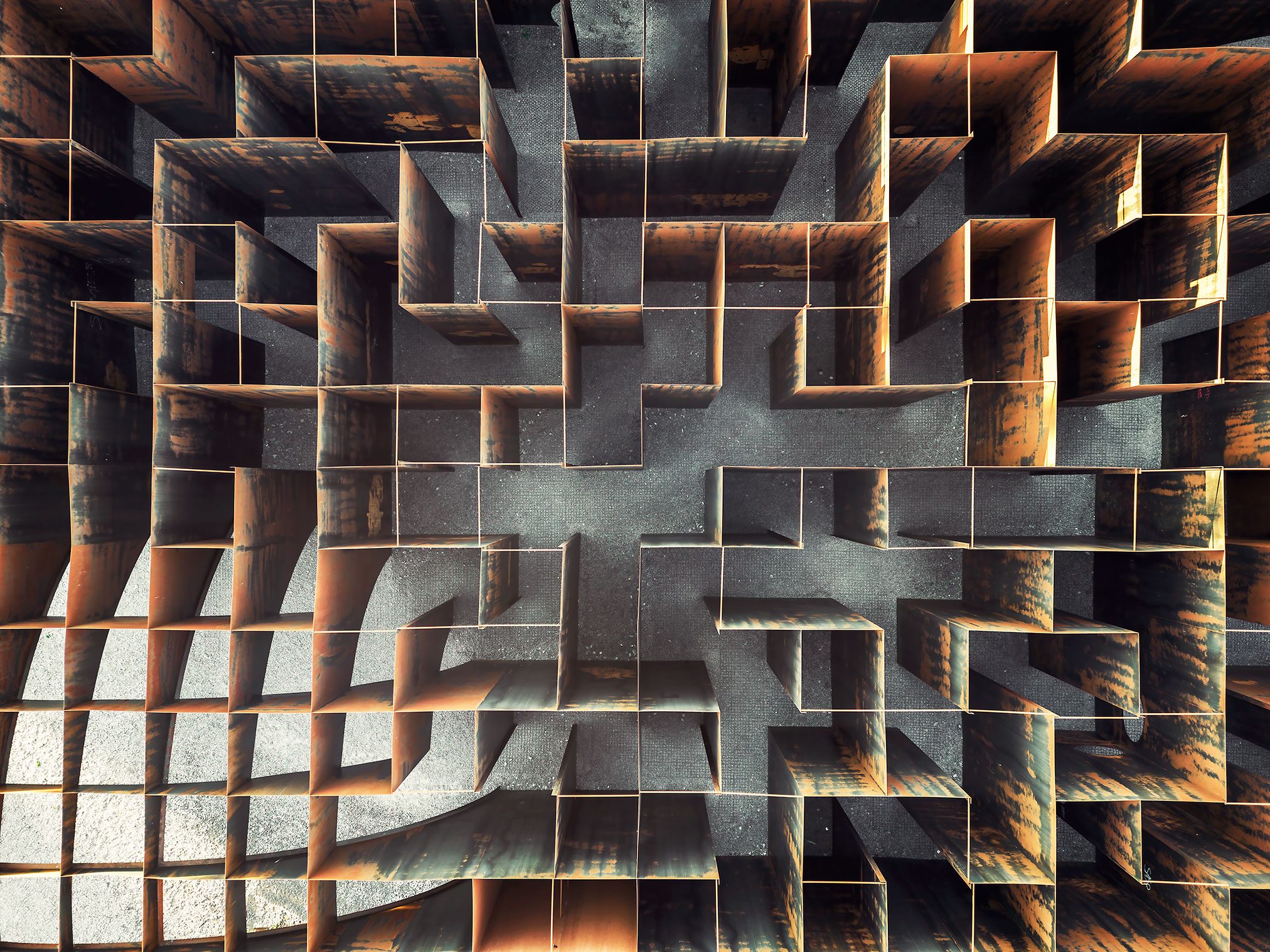 A rusted steel lattice labyrinth at an industrial monument in Belgium