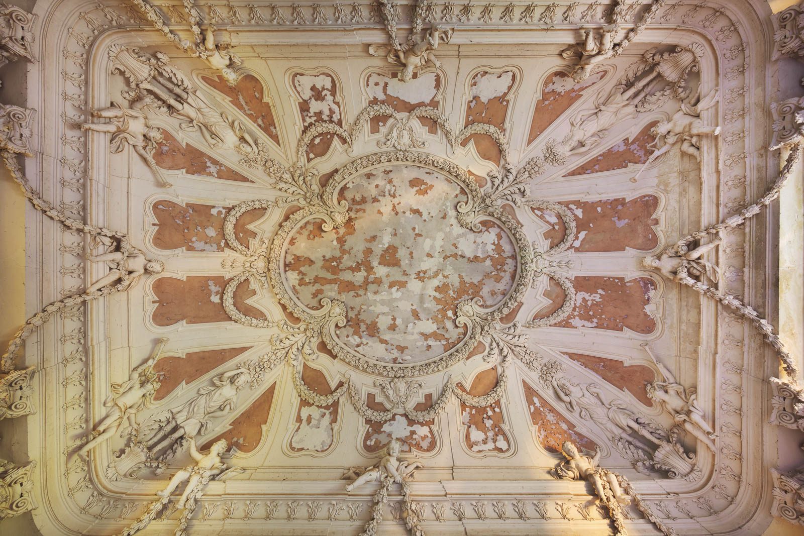 A frescoed ceiling with a putto medallion inside an abandoned villa in Italy