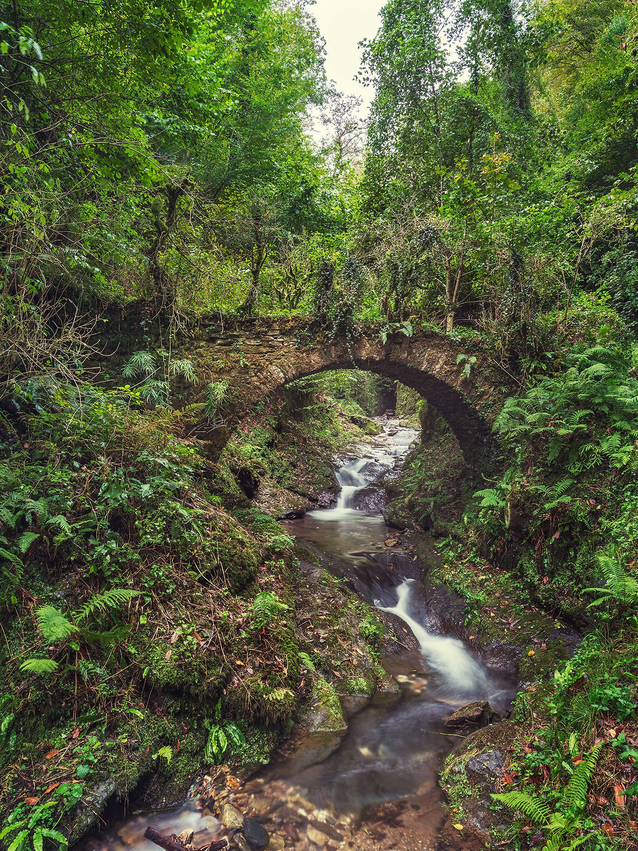 Tall stone arch above a waterfall gorge, Tuscany, Italy