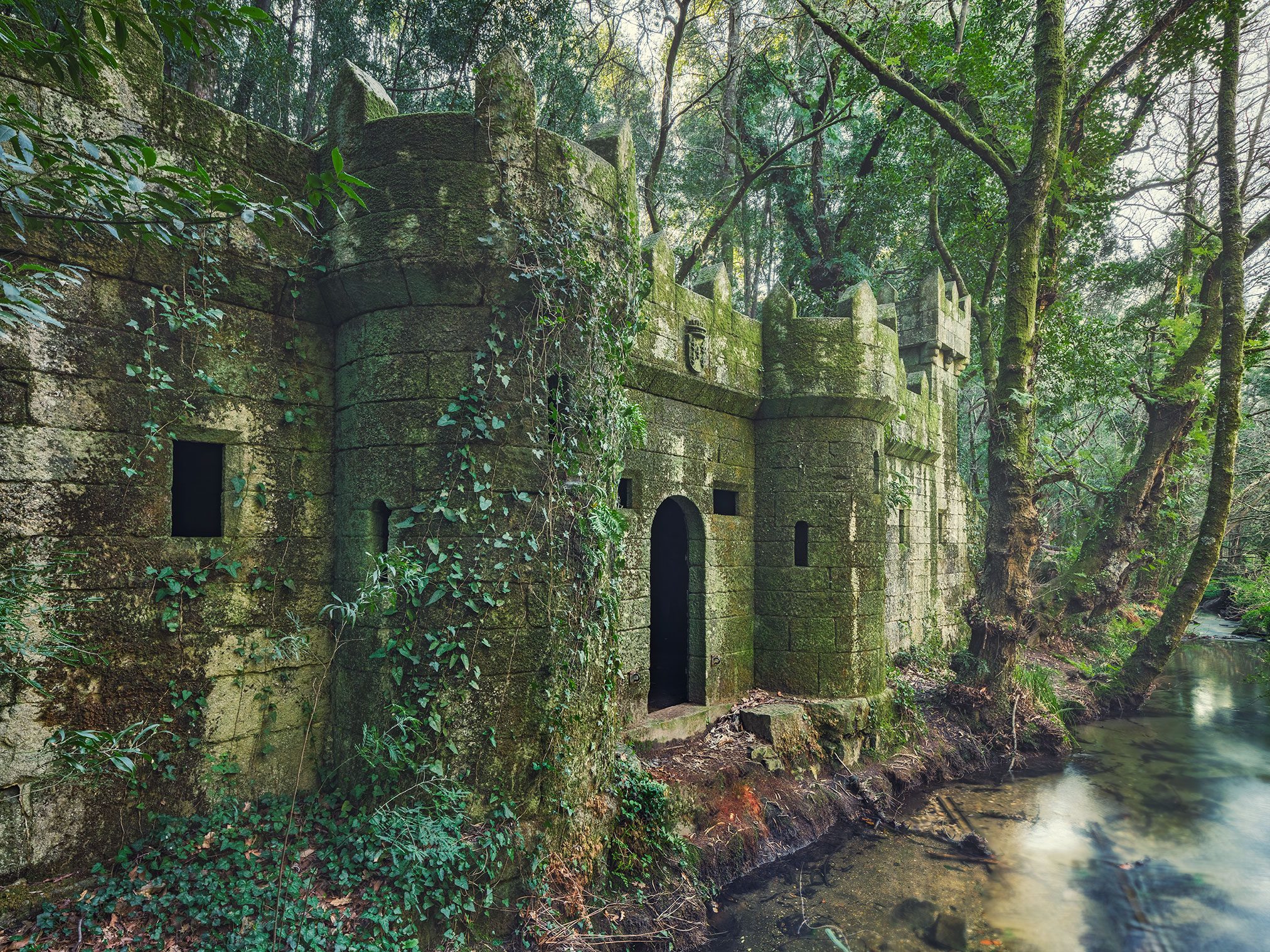 Moss covered fortified ruin with a tower in the forest, Spain