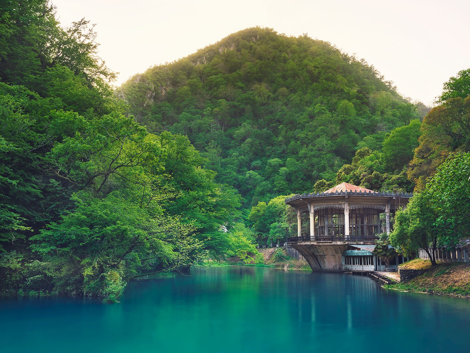 Historic station with a pavilion roof above a turquoise lake